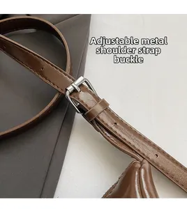 Detail of adjustable brown leather shoulder strap with silver metal pin buckle