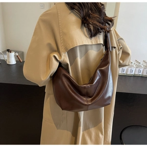 Detail of dark brown glossy PU leather hobo bag with smooth zipper and vertical stitching