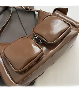 Detail of brown glossy PU leather crossbody bag with dual front square zip pockets