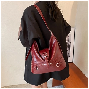 Close-up of vintage burgundy PU leather shoulder bag with silver hardware on a model