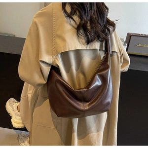 Detail of dark brown PU leather hobo bag with pebble grain worn with a beige coat