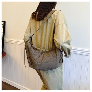Detail view of brown quilted crossbody bag with side drawstring and metal eyelets
