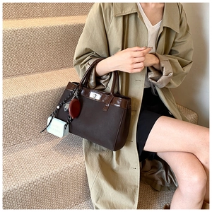 Detail of dark brown canvas tote bag with shiny leather trim and stylish metal lock
