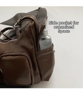 Detail view of the side storage pocket and zippers on this dark brown PU shoulder bag