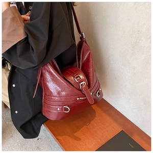 Detail of burgundy PU leather hobo bag with silver buckles and distressed texture