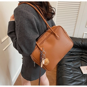 Détail latéral du sac à épaule en cuir PU marron avec bandoulière tissée décorative