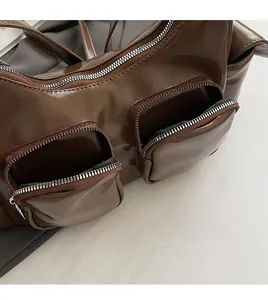Detail of dark brown glossy PU shoulder bag featuring dual front zipper pockets