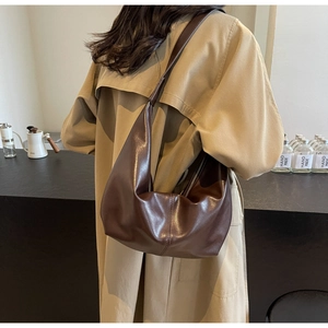 Detail of dark brown faux leather hobo bag with retro crescent shape and wide shoulder strap