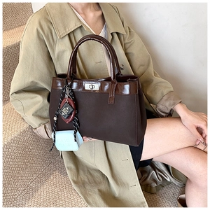 Detail view of a vintage brown PU leather and canvas tote with a Bible pendant charm