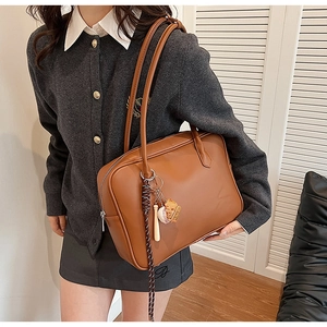 Vue détaillée du sac à bandoulière en cuir PU marron avec breloques de baseball et sangle