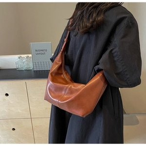 Brown vintage crescent PU leather shoulder bag shown on model in a minimalist setting