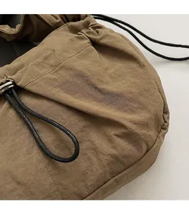 Dettaglio della borsa a tracolla in nylon marrone con trama pieghettata e cordoncino