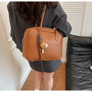 Gros plan d'un sac à bandoulière marron en cuir PU avec pendentif thème baseball