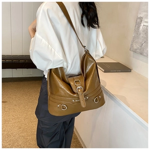 Detail of trendy caramel brown PU leather tote bag with glossy texture and metal buckles