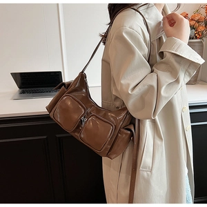 Detail of a deep brown shiny PU leather shoulder bag with functional zipper pockets