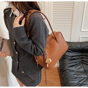 Détail du sac bandoulière en cuir PU marron avec un accessoire de charme ours en peluche