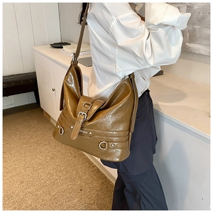 Detail of dark khaki PU leather shoulder bag with vintage silver metal buckles and straps