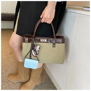 Detail of khaki canvas handbag with brown leather trim and decorative bag charms