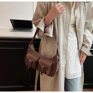 Detailansicht der dunkelbraunen Schultertasche aus Kunstleder mit Schnallen und Taschen