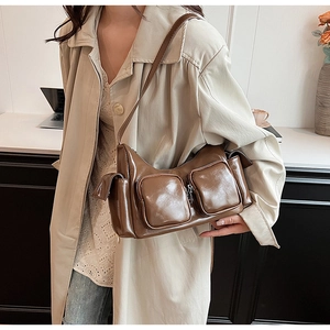 Detail of a brown glossy PU leather shoulder bag with multi-pocket utility design for women
