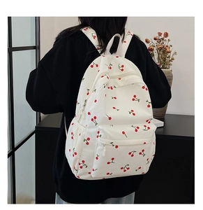 Détail du sac à dos en velours côtelé blanc avec imprimé cerise et poche avant zippée