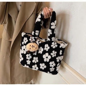 Detail der Plüsch-Tragetasche mit schwarz-weißem Blumenmuster und braunem Teddybär