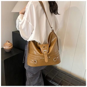Detail of caramel PU leather tote bag with thick strap and buckle on a shoulder