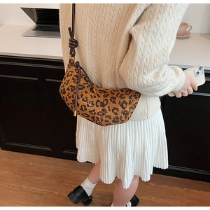 Détail du sac baguette en daim léopard avec bandoulière en cuir marron nouée à l'épaule