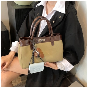 Detail of olive green canvas tote bag with dark brown leather handles and decorative charms