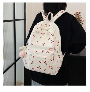 Détail d'un sac à dos blanc en velours côtelé avec imprimé cerise et pendentif rose