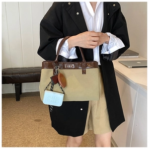 Detail of khaki canvas tote with brown leather trim, silver twist lock and mini charms
