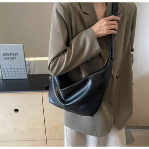 Minimalist black crescent crossbody bag in matte PU leather shown with wide shoulder strap