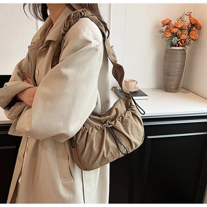 Foto lifestyle della borsa hobo in nylon kaki con texture a pieghe, coulisse e tracolla larga