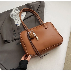 Sac à main marron en cuir PU avec pendentif baseball sur une veste de costume grise