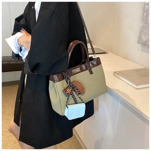 Detail of vintage canvas tote bag with brown faux leather trim and golden twist lock closure