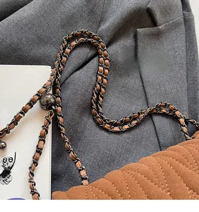 Close-up of brown quilted suede shoulder bag with V-shaped stitching and gold chain strap