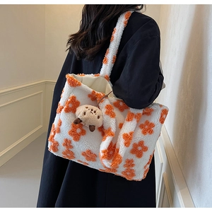 Detailaufnahme der weißen Plüschtasche mit orangen Blumenmustern und Bärenanhänger