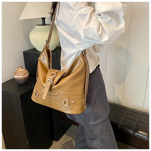 Detail view of caramel PU leather bag with buckled straps and silver hardware