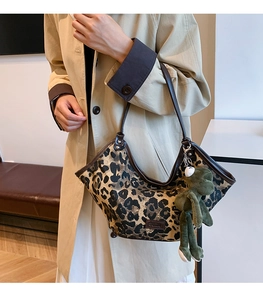 Détail d'un sac en toile léopard avec bordure en cuir et breloque en peluche de grenouille