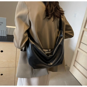 Model wearing a black PU leather half-moon shoulder bag with sleek gold zipper detail