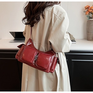 Macro detail of glossy dark red PU leather shoulder bag with functional dual zipper pockets