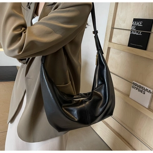 Detail of black crescent shoulder bag with gold zipper and premium leather texture