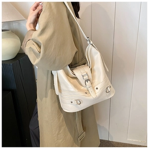 Detail view of cream PU leather shoulder bag featuring decorative stitching and metal buckles
