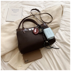 Detailed close-up of brown PU leather bag with silver twist lock and fashion charms