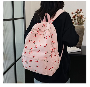 Sac à dos rose en velours côtelé avec motifs cerises porté par un mannequin stylé