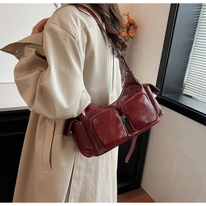 Detail of dark red glossy PU leather shoulder bag with two functional front zipper pockets