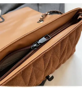 Detail of a brown quilted PU crossbody bag showing the smooth metal zipper closure