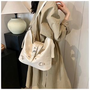 Detailed side view of a cream PU leather crossbody bag with silver studs and D-ring hardware