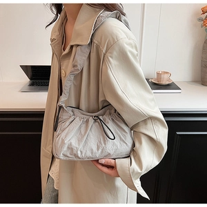 Dettaglio della borsa a tracolla in nylon grigio chiaro con pieghe e trench elegante