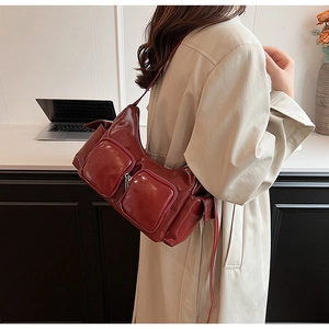 Detail of a burgundy high-shine PU leather shoulder bag with vintage multi-pocket design
